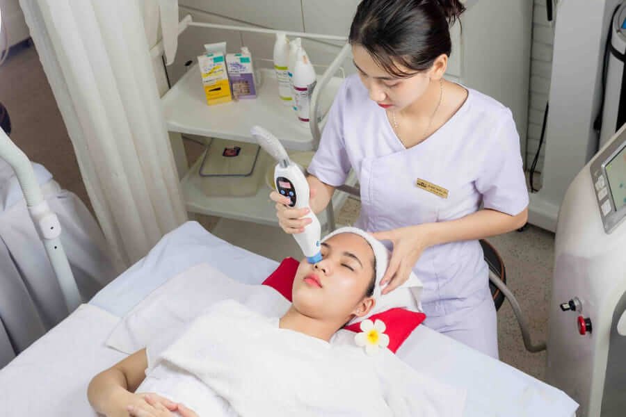 Chuyên viên thẩm mỹ thực hiện chăm sóc da mặt cho khách hàng tại spa, sử dụng thiết bị chuyên dụng.