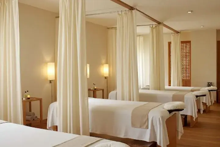 Phòng spa thư giãn với nội thất sang trọng, giường mát-xa và rèm trắng tạo không gian yên bình.