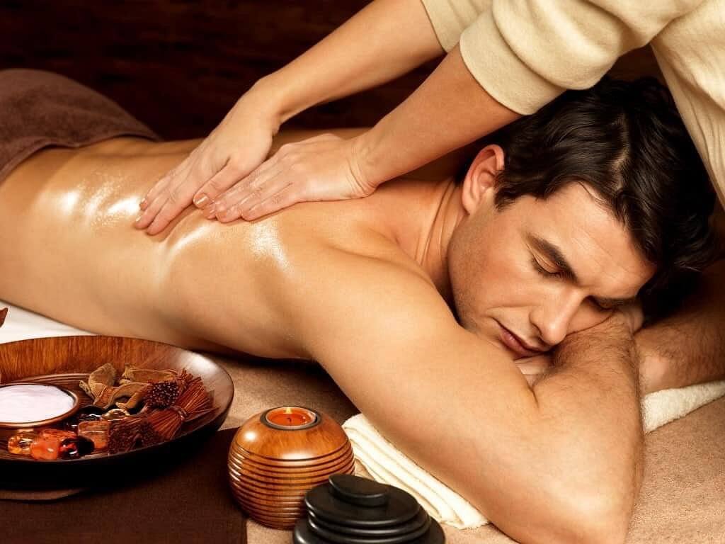 Người đàn ông thư giãn với liệu pháp massage, với dầu và nến tạo không gian thư giãn hoàn hảo.