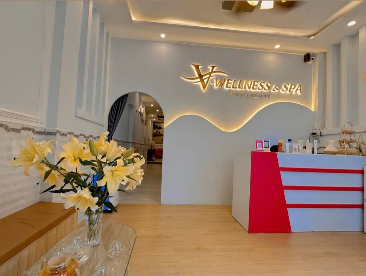 Quầy lễ tân spa với hoa ly vàng trang trí, bảng hiệu Wellness & Spa trong không gian sang trọng.