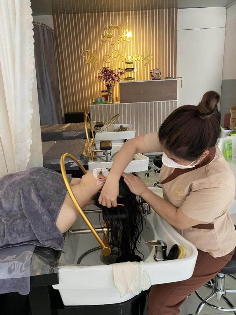 Nhân viên spa gội đầu cho khách hàng tại tiệm làm đẹp, không gian sang trọng và thư giãn.