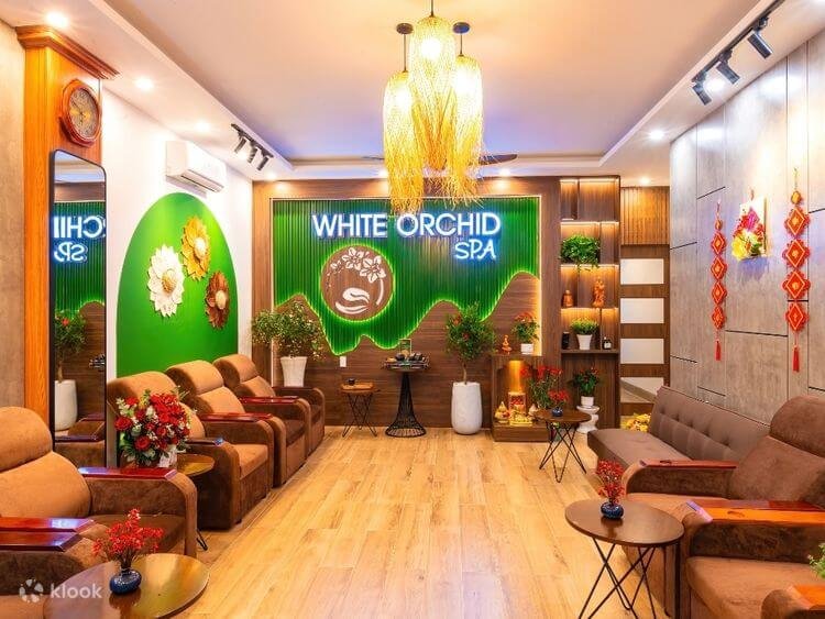 Spa White Orchid với nội thất sang trọng, ghế thư giãn, trang trí hoa và ánh đèn ấm cúng.