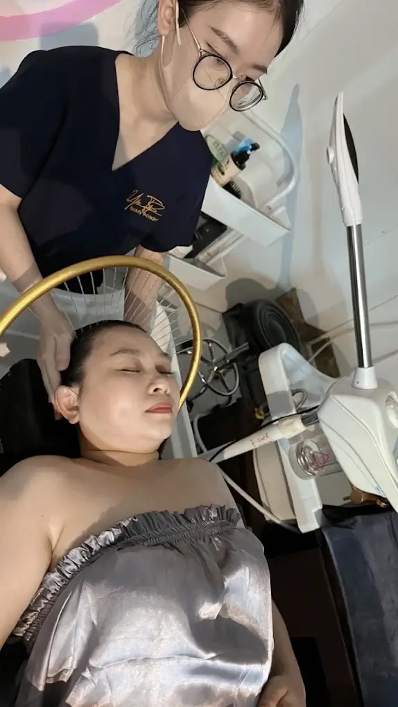 Nhân viên thẩm mỹ thực hiện trị liệu da mặt cho khách hàng tại spa với thiết bị hiện đại.