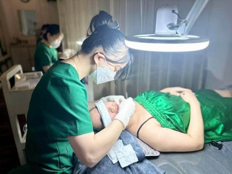 Nhân viên spa thực hiện liệu trình chăm sóc da mặt cho khách hàng trong phòng điều trị thẩm mỹ.