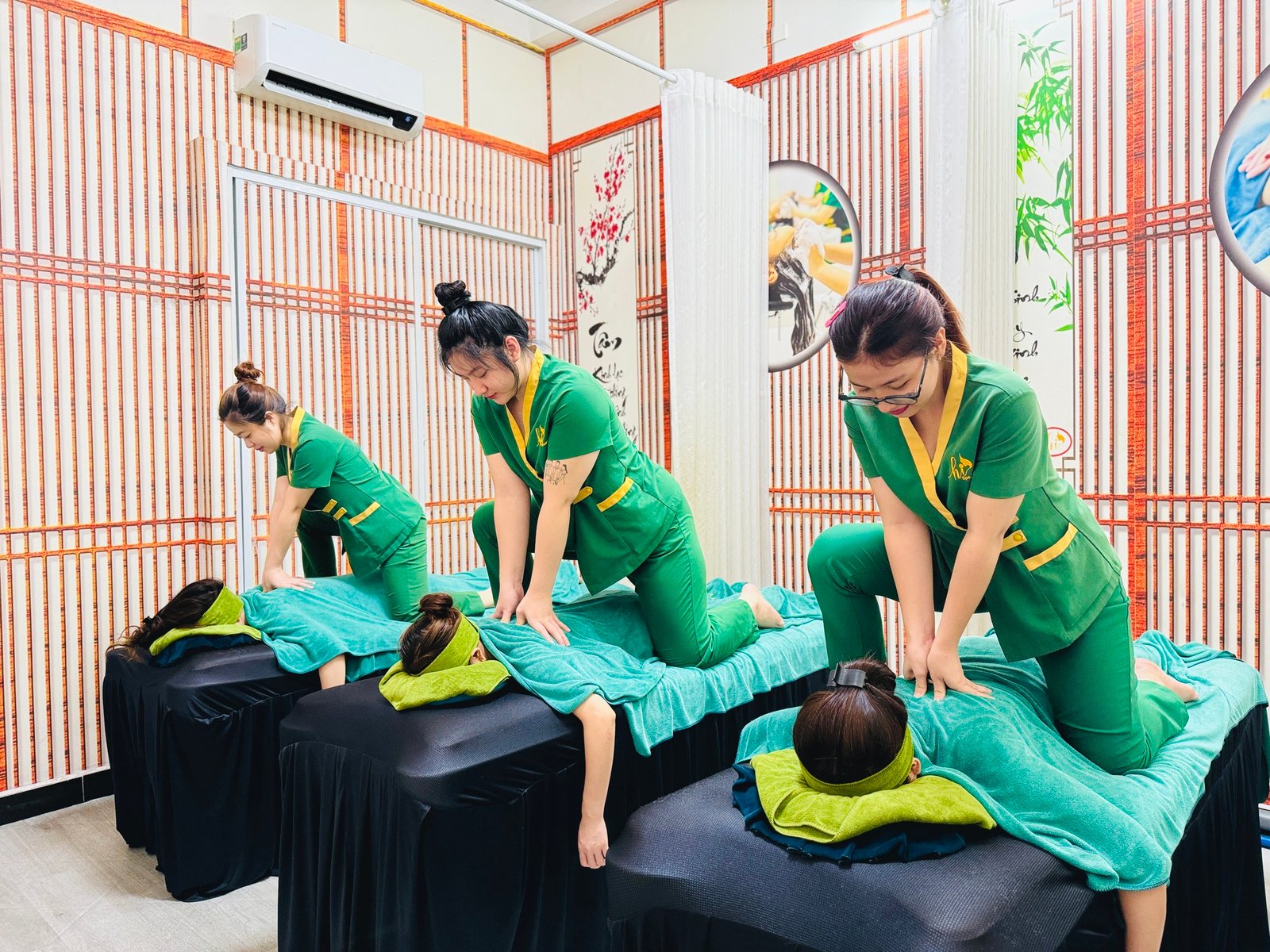 Nhân viên spa thực hiện liệu pháp massage thư giãn trên khách hàng tại phòng trị liệu trang trí tre.