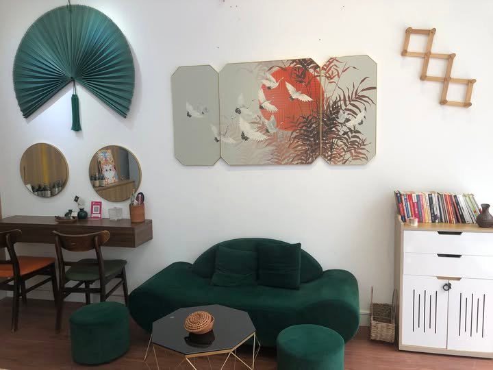 Phòng khách trang trí phong cách, sofa xanh lá, tủ sách và tranh nghệ thuật tạo điểm nhấn hiện đại ấm cúng.