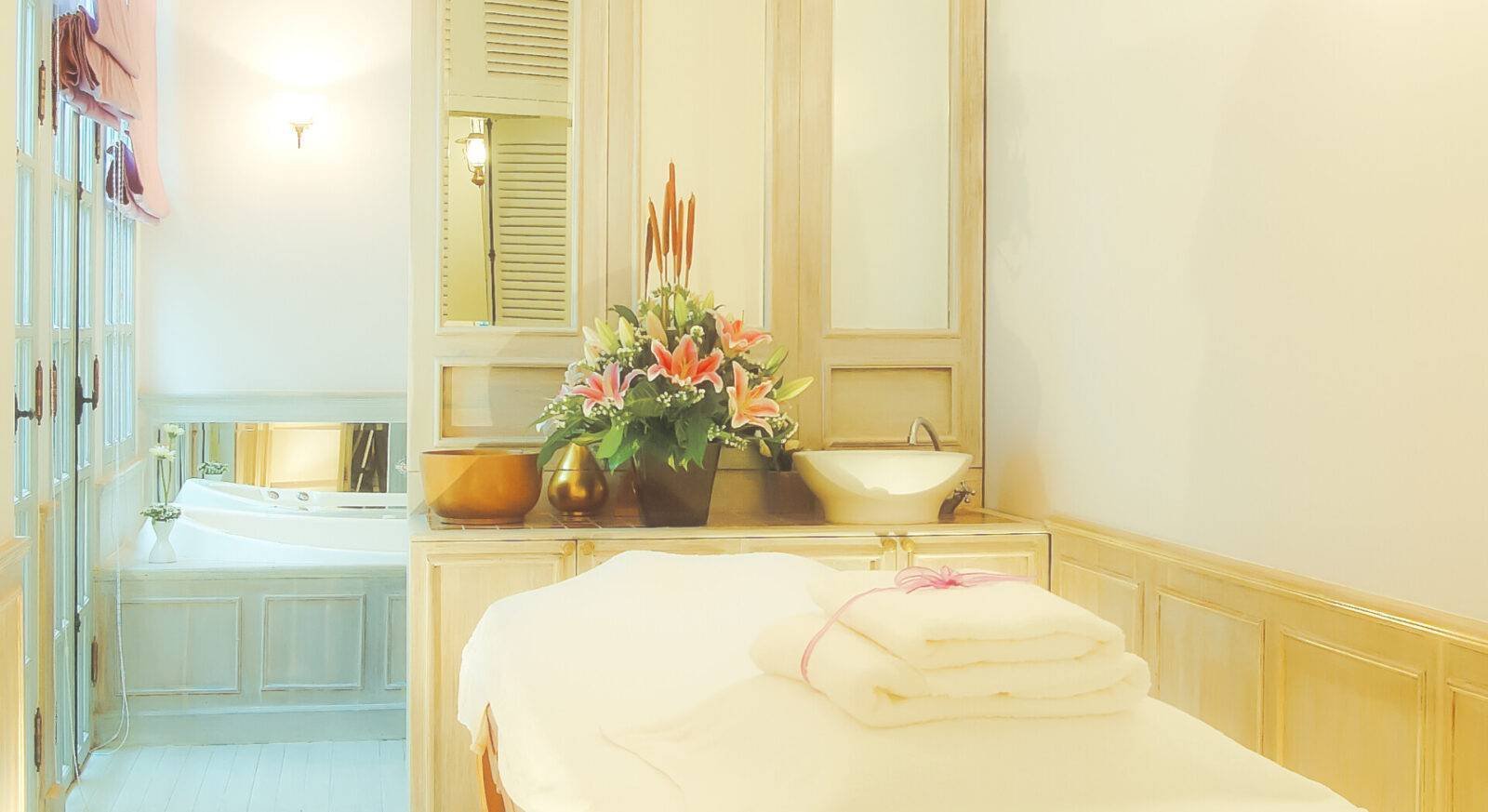 Phòng spa thư giãn với hoa tươi trên bàn massage, ánh sáng ấm cúng.