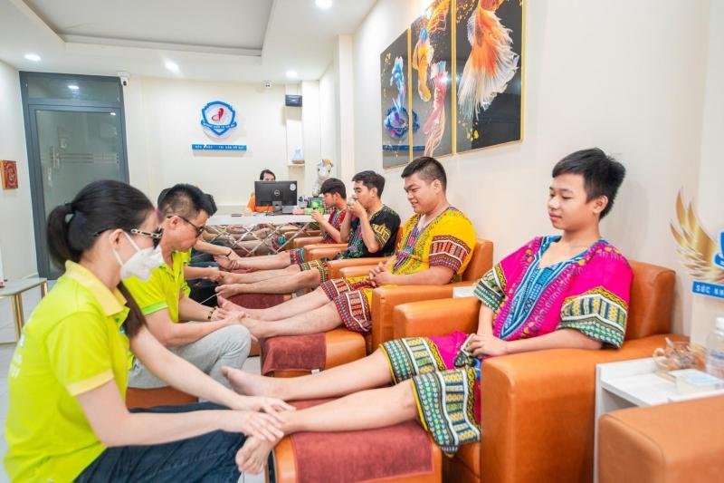 Nhân viên mát xa chân cho nhóm nam giới mặc áo truyền thống trong spa, thư giãn và tận hưởng dịch vụ.