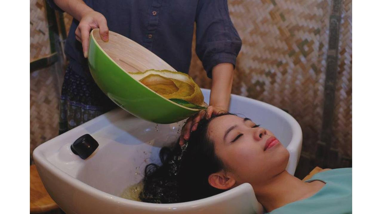 Người phụ nữ thư giãn trong spa được gội đầu với nước bưởi, phong cách chăm sóc tóc tự nhiên.