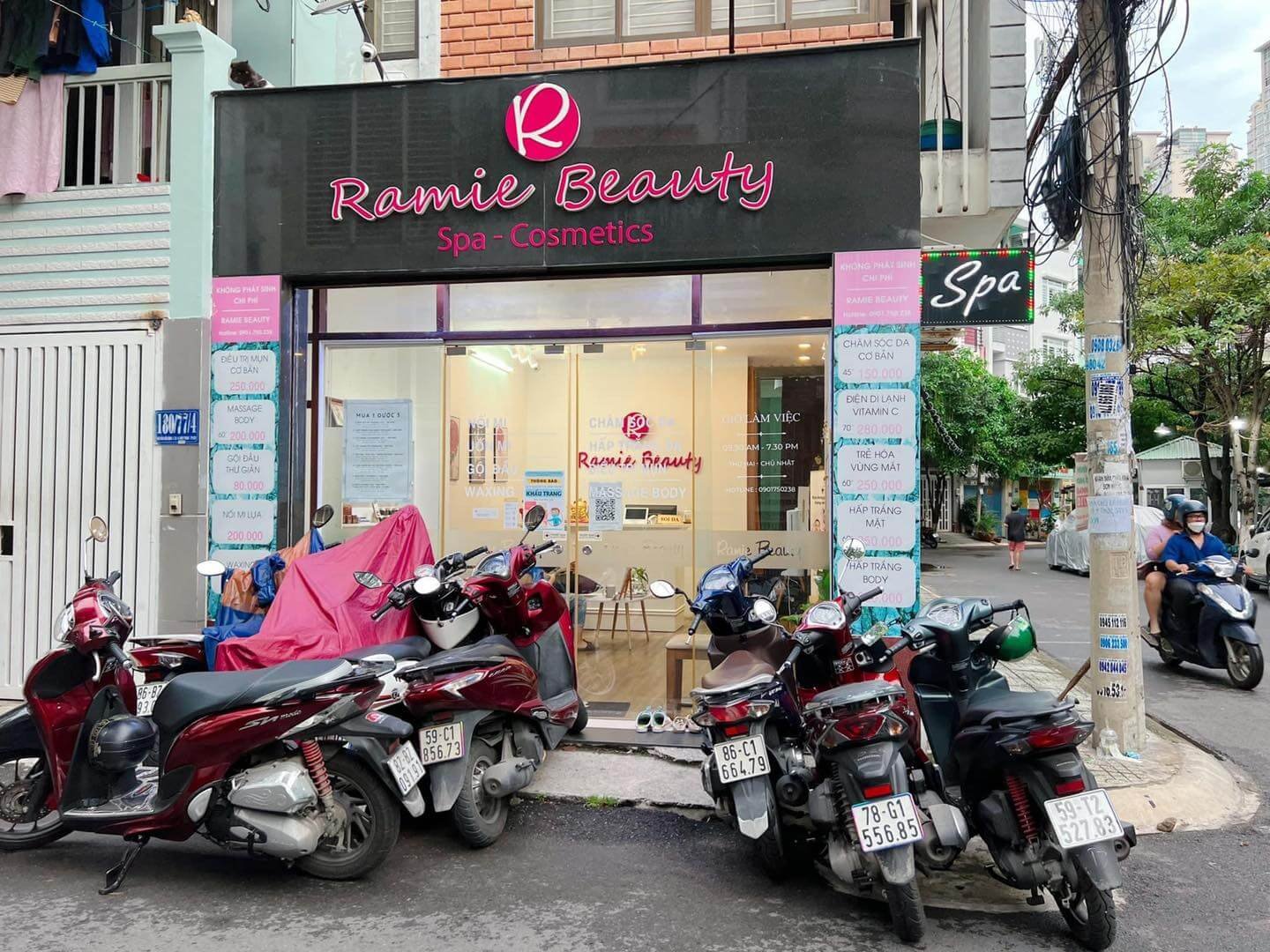 Mặt tiền tiệm làm đẹp Ramie Beauty Spa - Cosmetics với nhiều xe máy đậu phía trước trên đường phố.