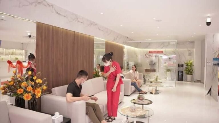 Phòng chờ spa hiện đại với ghế sofa và trang trí hoa, nhân viên đang tư vấn khách hàng.