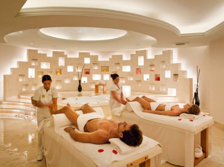 Dịch vụ spa cao cấp, hai người đang được mát-xa trong phòng spa sang trọng, thư giãn với ánh sáng ấm áp.