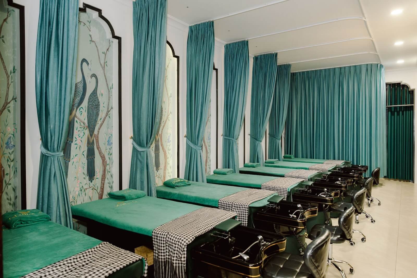 Phòng spa sang trọng với bảy giường massage và rèm xanh tạo không gian thư giãn.