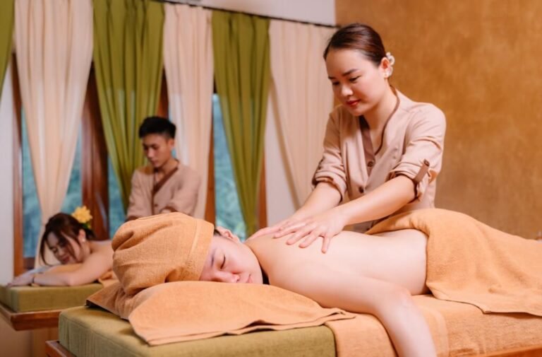 Nhân viên spa thực hiện massage thư giãn cho khách hàng trên giường trong không gian ấm áp.