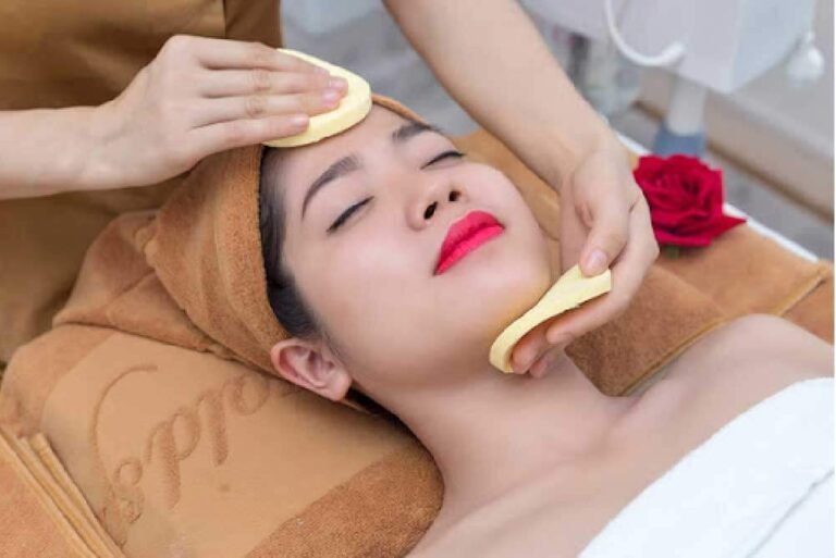 Người phụ nữ thư giãn với liệu pháp chăm sóc da mặt, khăn quấn đầu và hoa hồng đỏ bên cạnh.