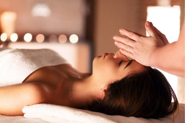 Người phụ nữ thư giãn nhận xoa bóp mặt tại spa, không gian ấm cúng với ánh đèn mờ.