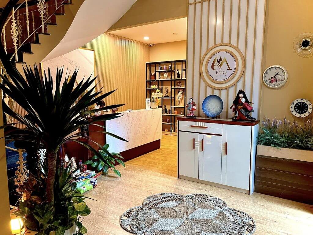 Không gian nội thất hiện đại với quầy lễ tân sáng tạo, cây xanh và đồng hồ treo tường trang trí.