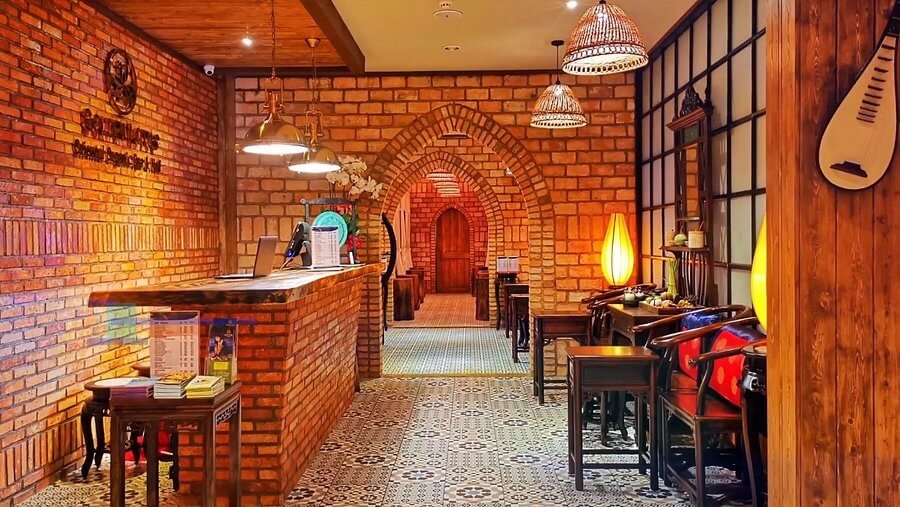 Quầy lễ tân trong khách sạn phong cách cổ điển, tường gạch đỏ, ánh sáng ấm áp tạo cảm giác thư giãn.