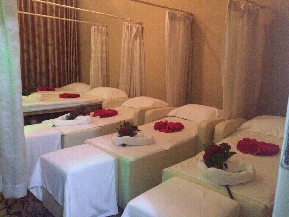 Phòng spa thư giãn với giường massage được trang trí khăn gấp hình hoa, không gian ấm cúng và sang trọng.