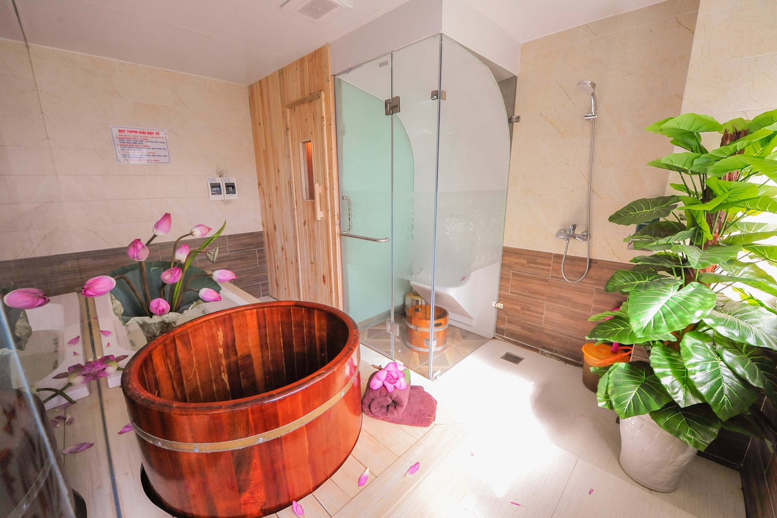 Phòng tắm sang trọng với bồn tắm gỗ, hoa sen và cây xanh, tạo không gian thư giãn và gần gũi thiên nhiên.