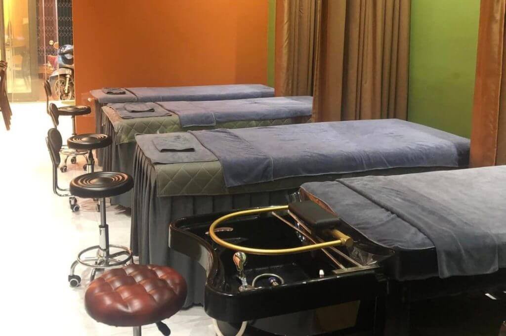 Giường massage và ghế xoay trong phòng spa màu sắc ấm áp, dành cho chăm sóc sức khỏe và thư giãn.