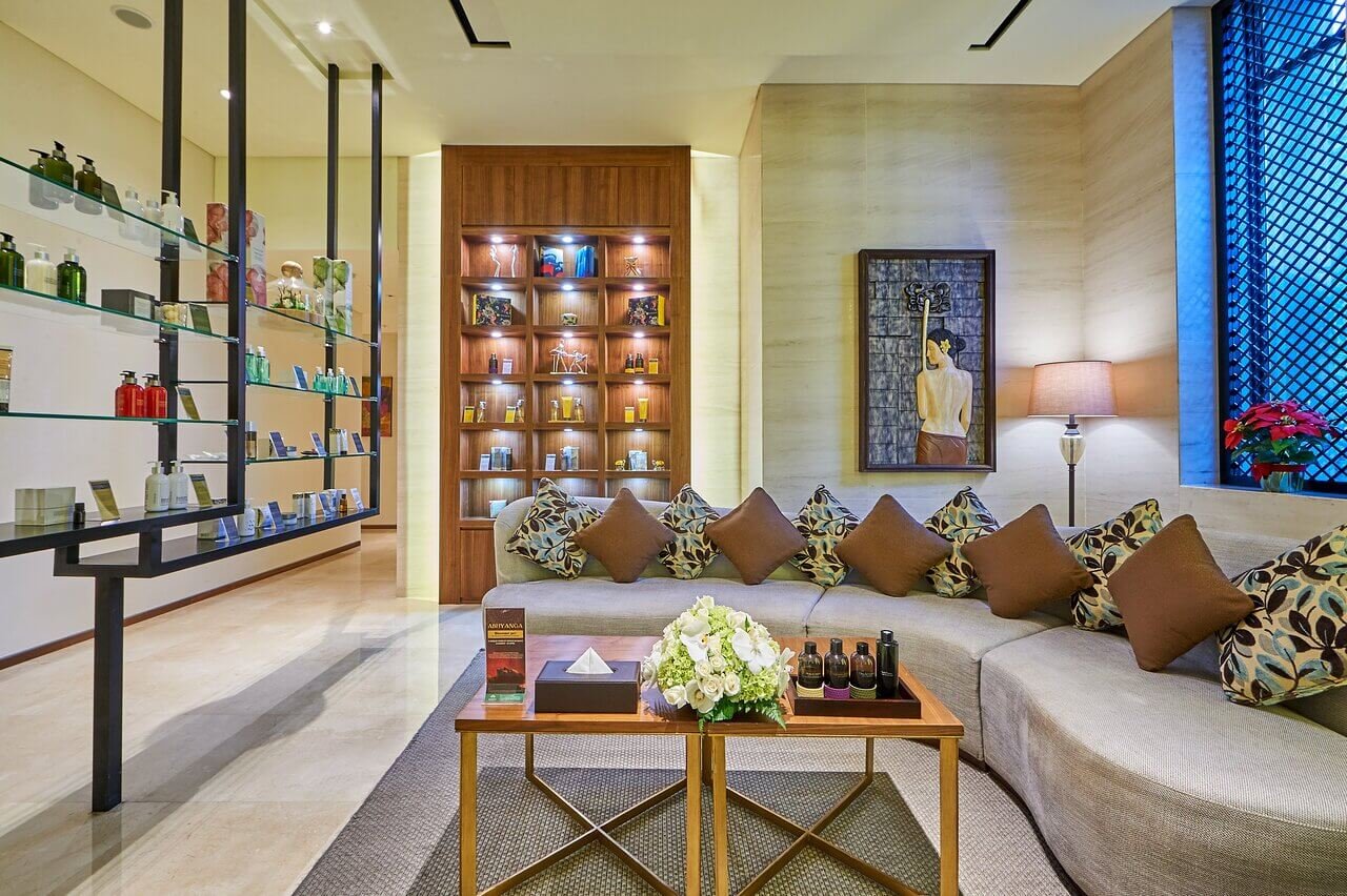 Phòng khách sang trọng với ghế sofa, bàn trà và kệ trưng bày sản phẩm chăm sóc spa.