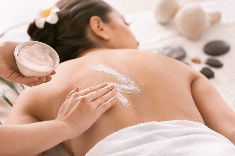 Người phụ nữ đang được massage lưng với kem dưỡng trong spa thư giãn.