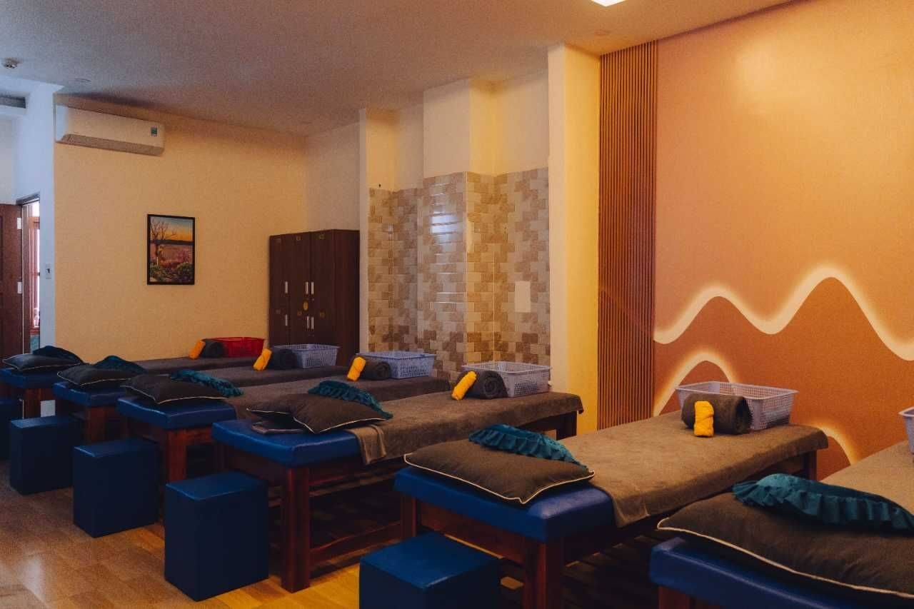 Phòng spa với nhiều giường massage được sắp xếp ngay ngắn, ánh sáng ấm áp và trang trí tường đơn giản.