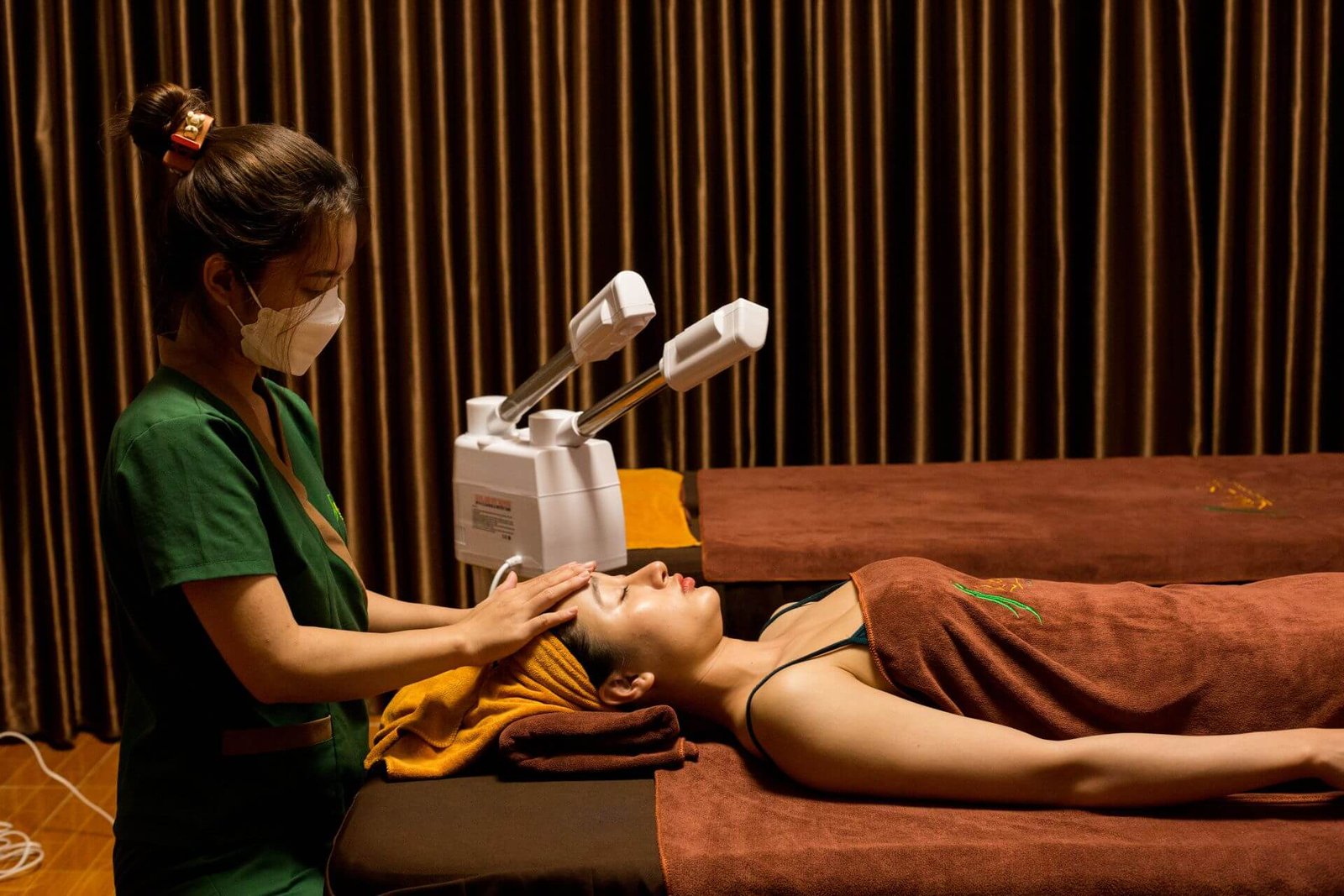 Nhân viên spa đang mát-xa mặt cho khách hàng thư giãn trong không gian ấm cúng, chuyên nghiệp.