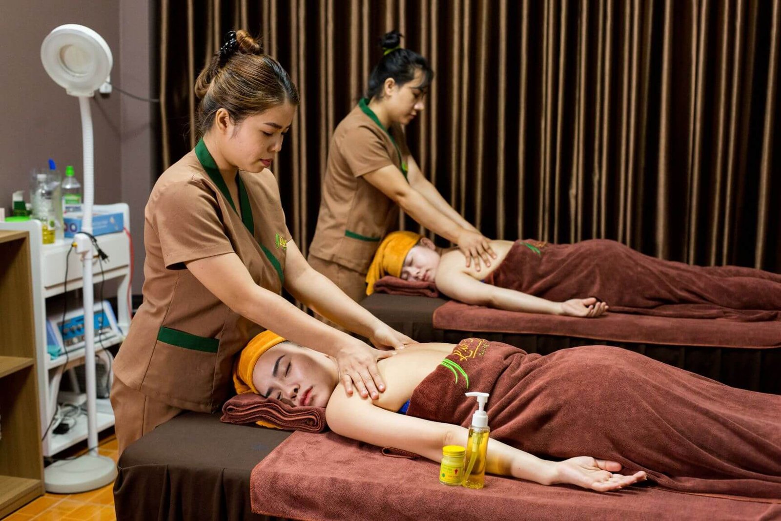 Nhân viên spa massage khách hàng nằm trên giường, mang lại sự thư giãn thoải mái.