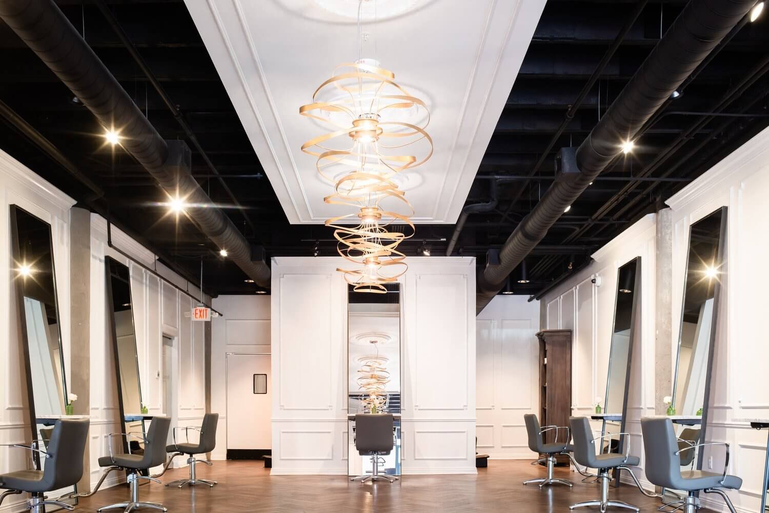 Salon tóc hiện đại với ghế và gương; trần nhà trang trí đèn treo nghệ thuật.