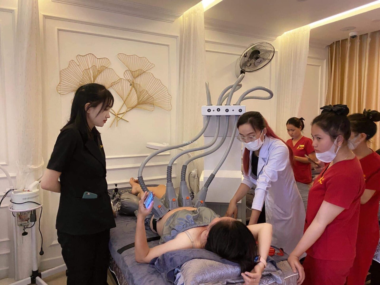 Nhân viên spa thực hiện liệu pháp chăm sóc cơ thể với máy móc hiện đại trong phòng trị liệu.