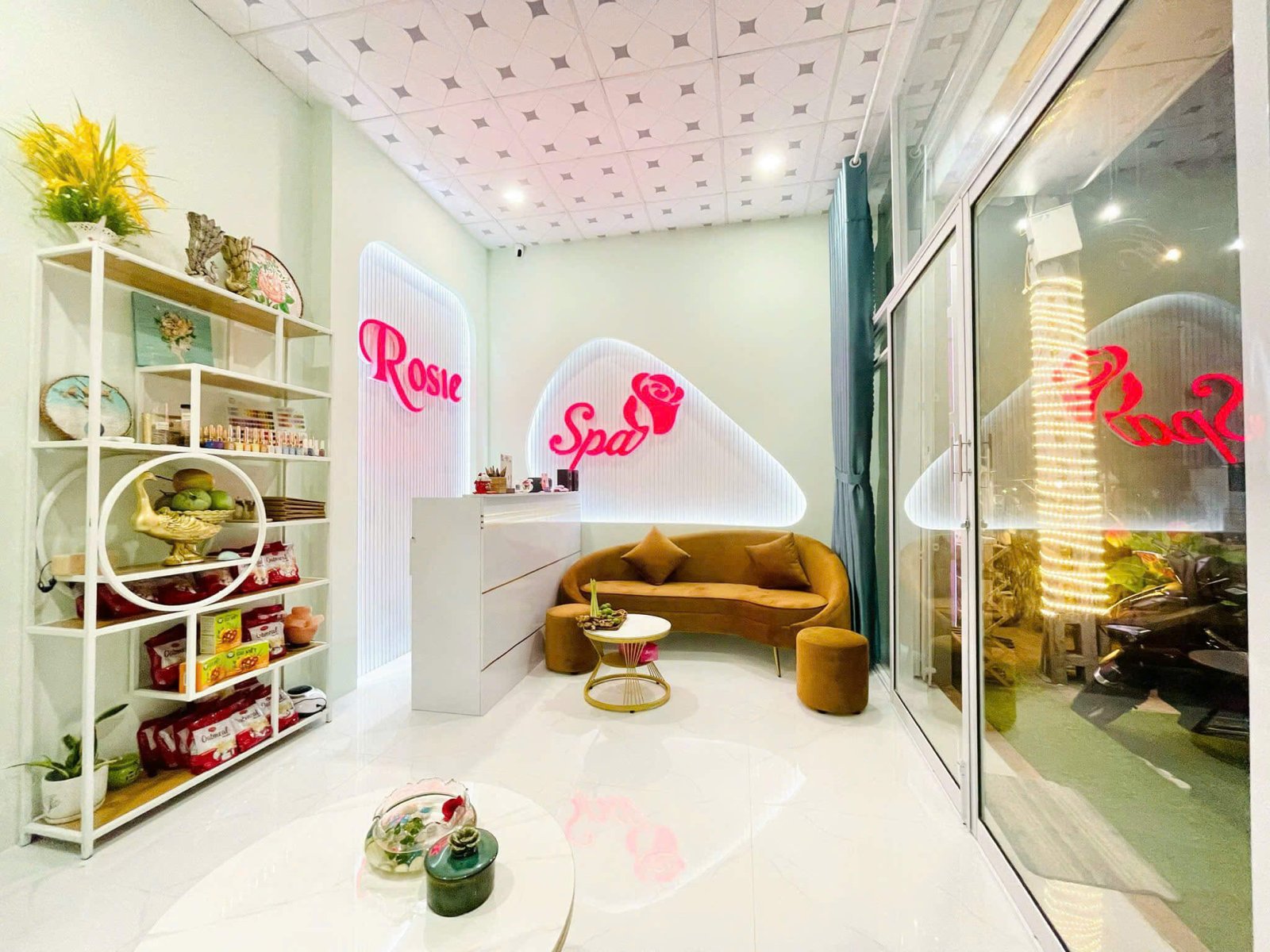 Phòng chờ spa sang trọng với bàn ghế hiện đại và trang trí hoa, ánh sáng ấm áp tại Rosie Spa.