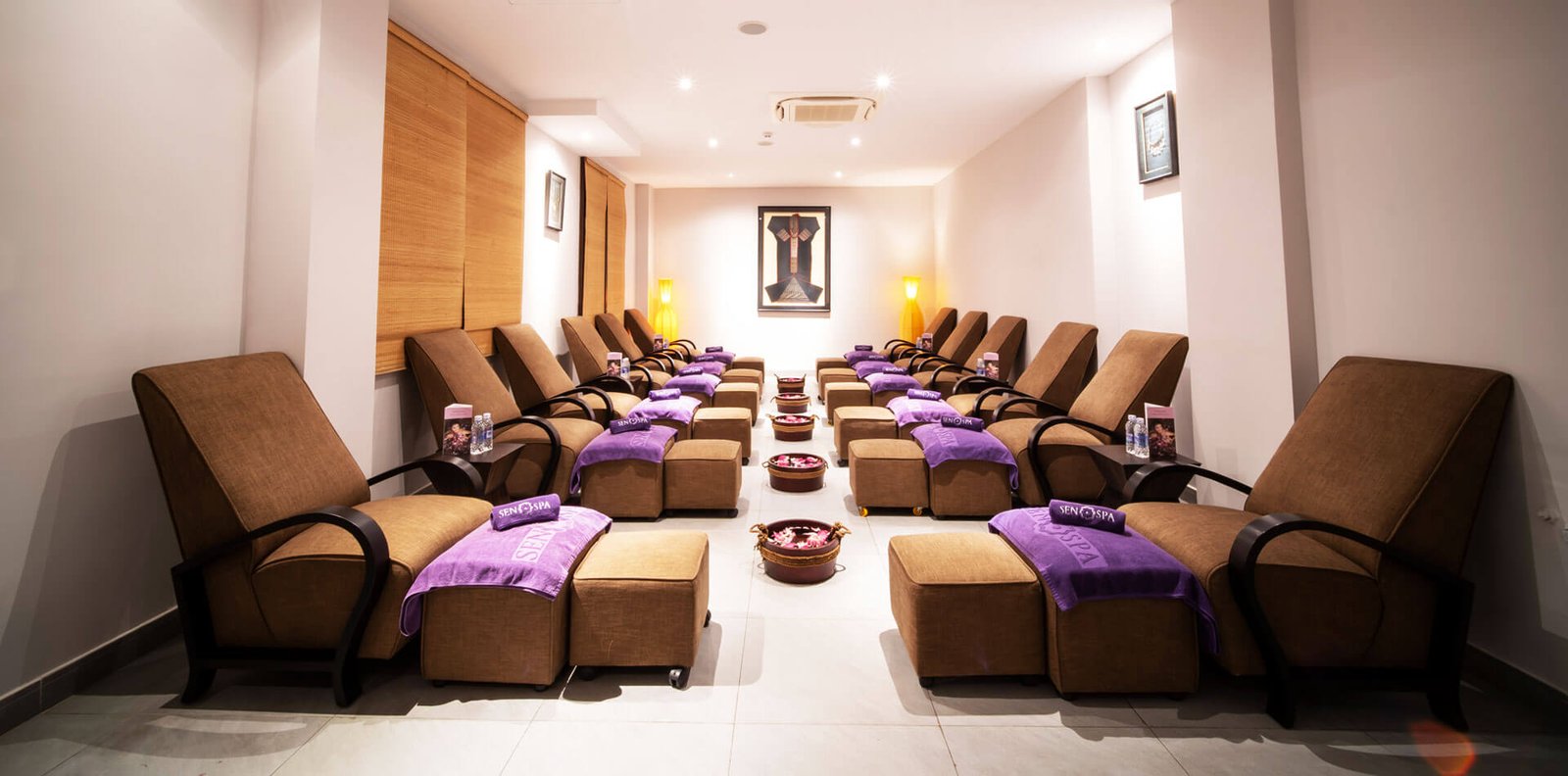 Phòng thư giãn sang trọng với ghế massage, khăn màu tím và ánh sáng dịu nhẹ tại spa cao cấp.