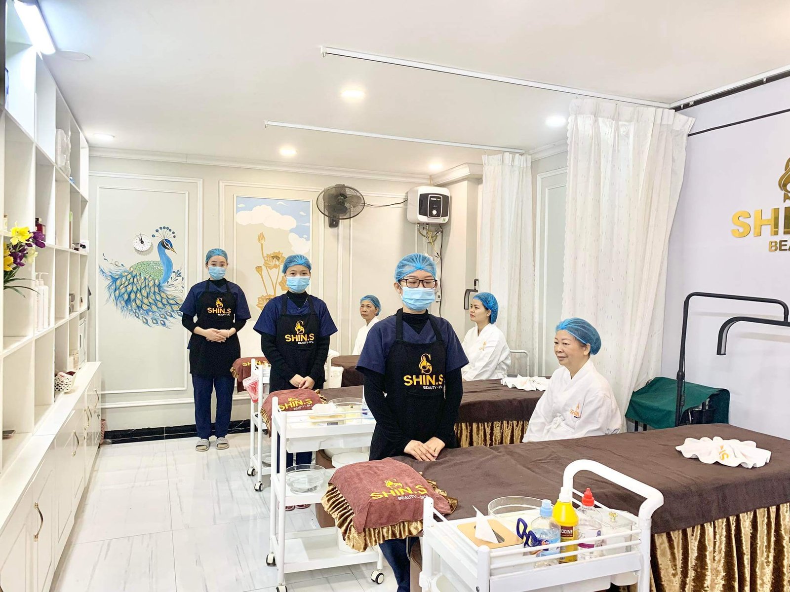 Nhân viên spa trong đồng phục và khẩu trang tại cơ sở làm đẹp, chuẩn bị dịch vụ chăm sóc da.