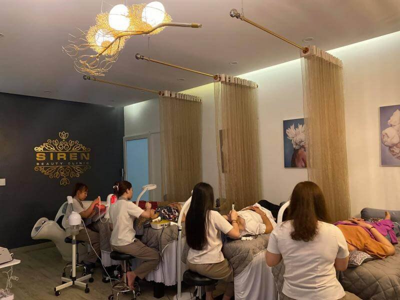 Phòng spa với nhân viên chăm sóc da cho khách hàng tôn lên không gian thư giãn tại phòng khám Siren Beauty.