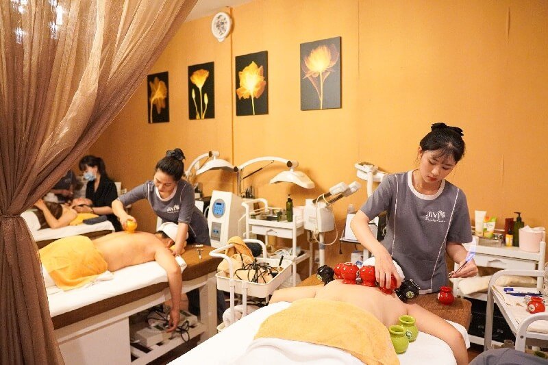 Nhân viên spa thực hiện liệu pháp giác hơi và massage trong phòng thư giãn, tạo không gian thoải mái và sang trọng.