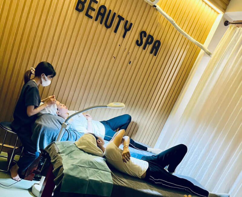 Nhân viên spa chăm sóc khách hàng nam nằm thư giãn tại một spa làm đẹp chuyên nghiệp.