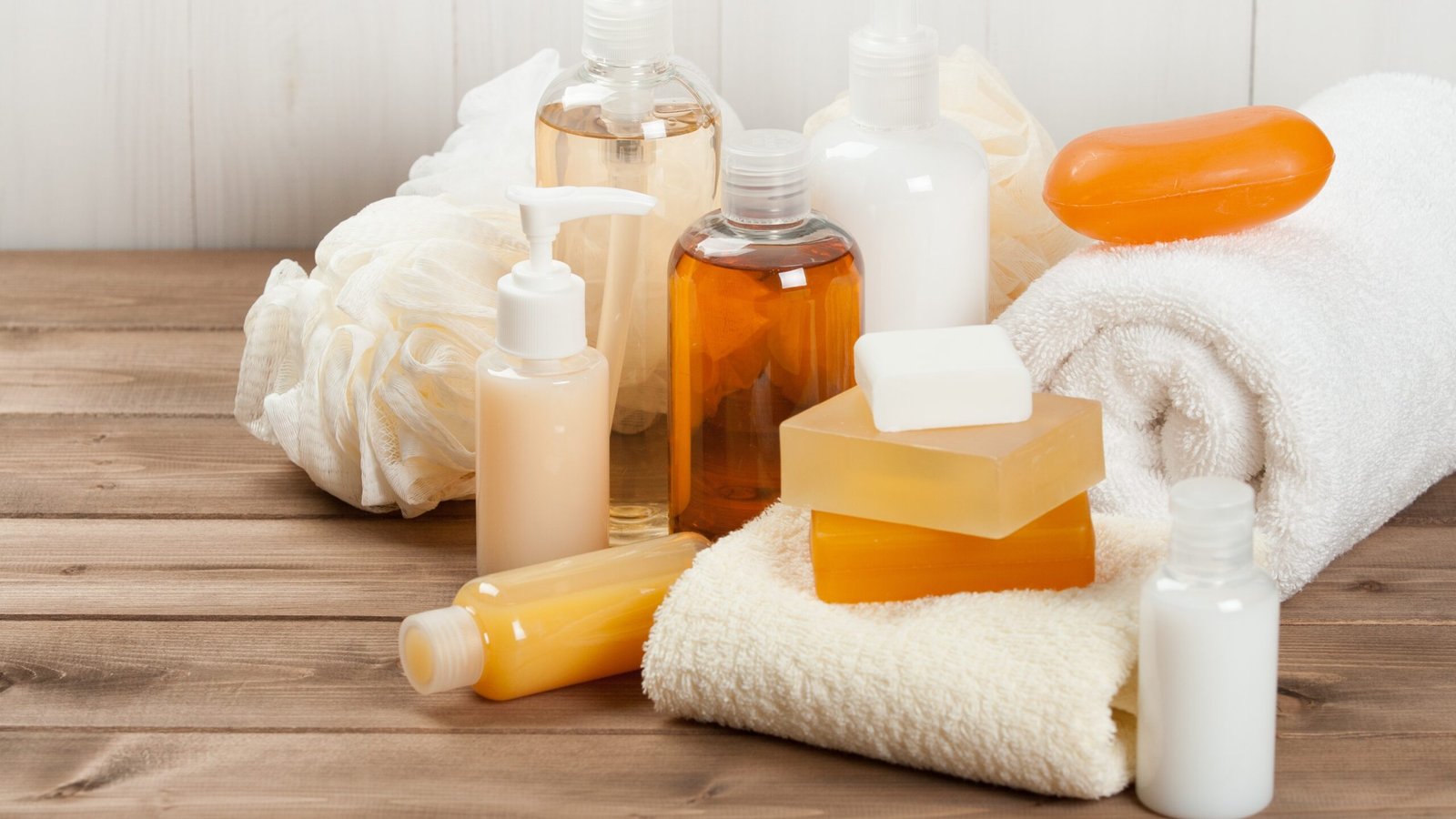 Sản phẩm tắm dưỡng da, khăn tắm và xà phòng trên bàn gỗ, chăm sóc cá nhân hàng ngày.