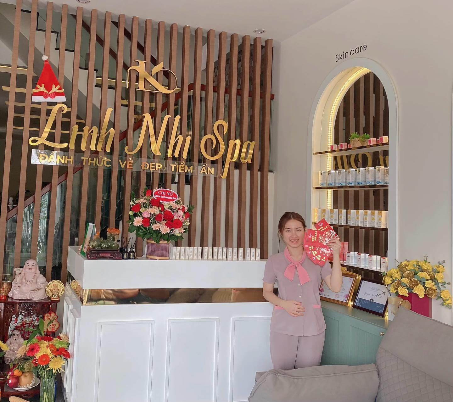 Nhân viên tại Linh Nhi Spa đứng trước quầy lễ tân, cầm phong bì đỏ, không gian trang trí ấm cúng.