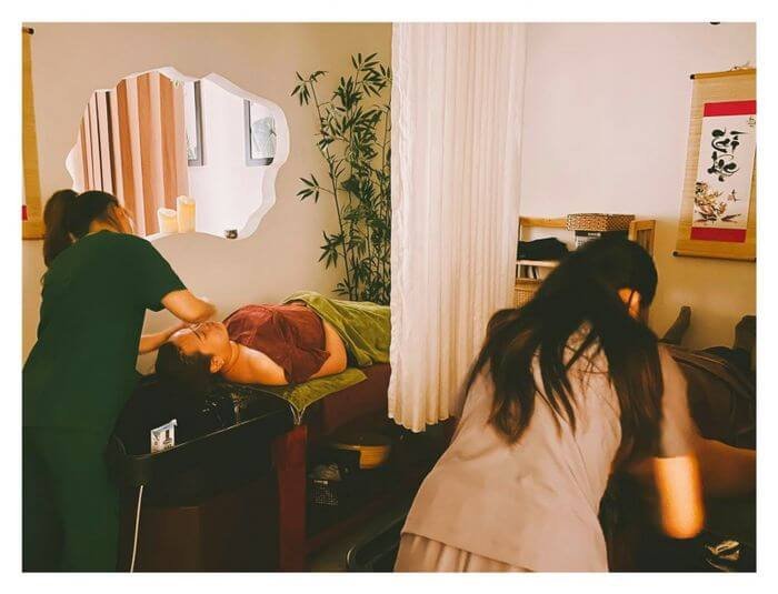 Nhân viên massage chăm sóc khách hàng thư giãn trong spa với không gian ấm cúng và trang trí tinh tế.