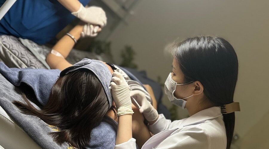 Nhân viên spa chăm sóc khách hàng đắp mặt nạ, mang khẩu trang phòng COVID-19, tạo sự an toàn và thư giãn.
