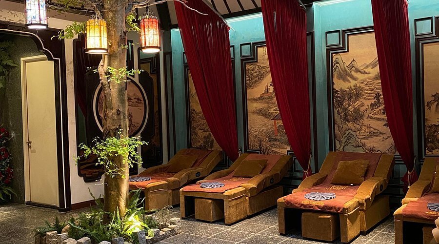 Phòng thư giãn với ghế nằm, đèn lồng treo và tranh tường phong cảnh, tạo không gian ấm cúng và thư thái.