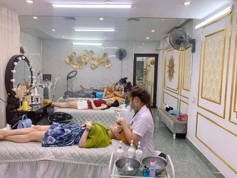Các khách hàng đang nằm trên giường trong một spa, nhân viên đang chăm sóc da mặt cho một người.