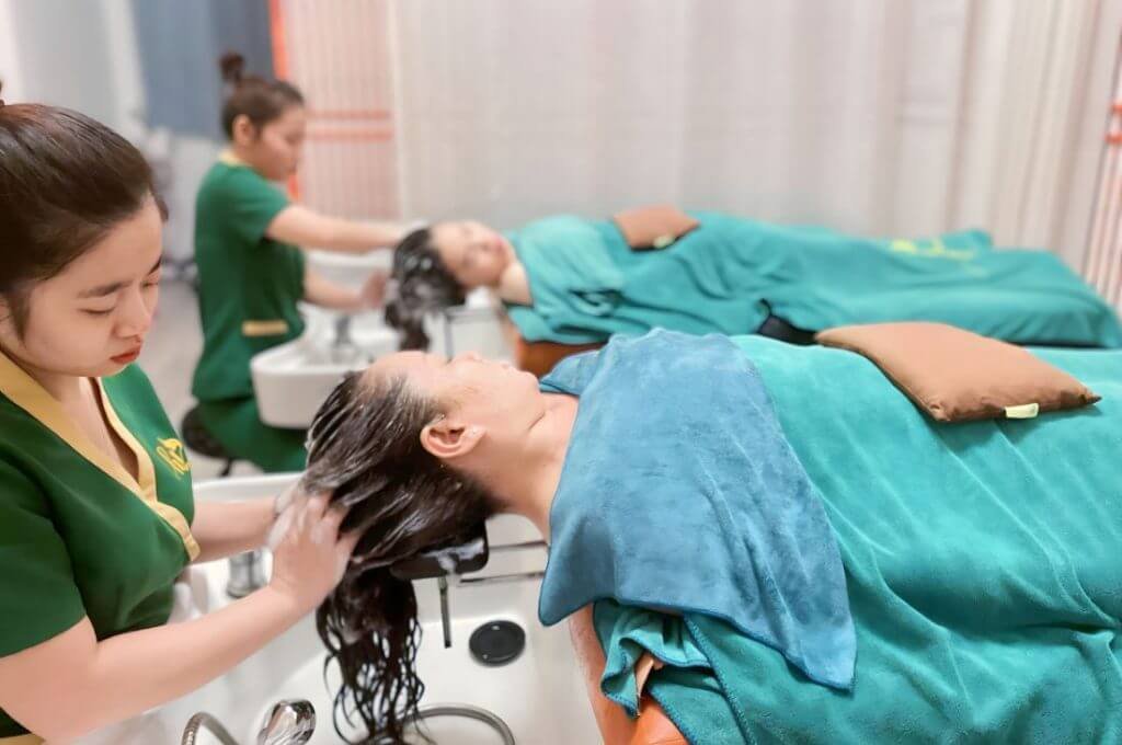 Nhân viên chăm sóc tóc cho khách hàng tại salon, mang đến dịch vụ thư giãn và phục hồi tóc.