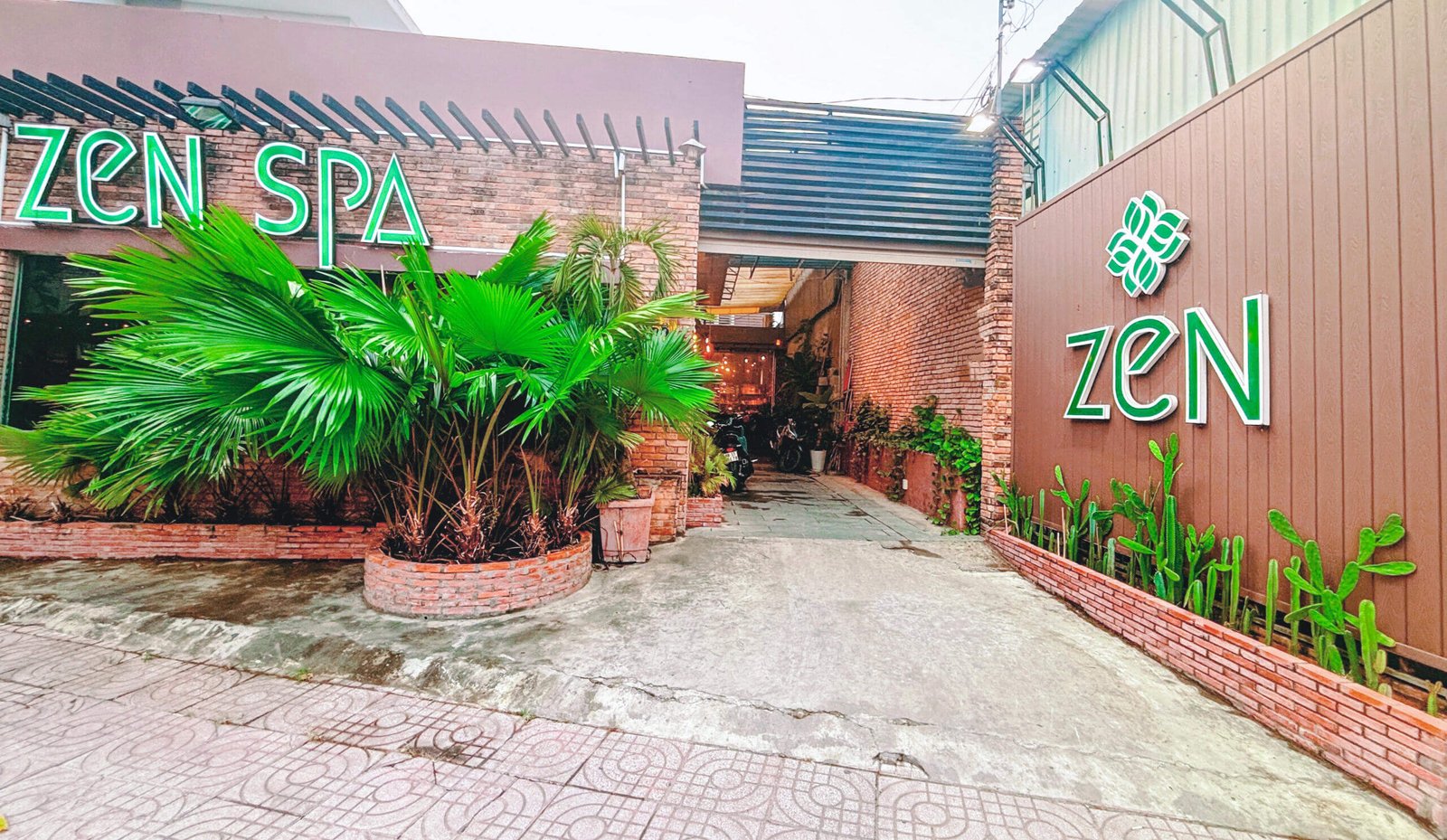 Lối vào Zen Spa với cây xanh và không gian thư giãn bên ngoài, thiết kế hiện đại và thư thái.