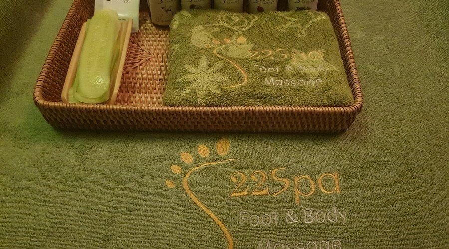 Khăn và sản phẩm spa trên nền màu xanh lá cây, được đặt trong giỏ mây, tạo cảm giác thư giãn và sang trọng.