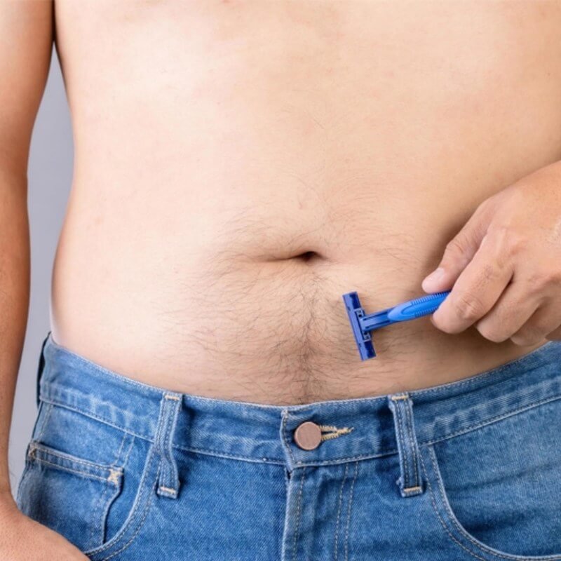 Người cầm dao cạo màu xanh đang cạo lông bụng trong khi mặc quần jeans xanh.