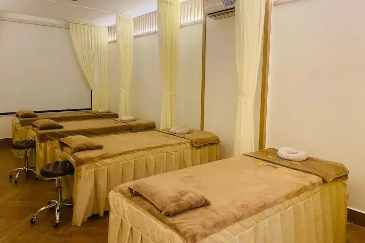 Phòng spa với bốn giường massage màu nâu nhạt, có rèm ngăn cách và ghế xoay bên cạnh.