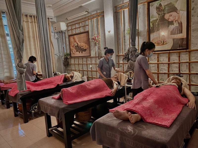 Ba người đang được massage trong một spa, với các chuyên viên chăm sóc đứng bên cạnh.